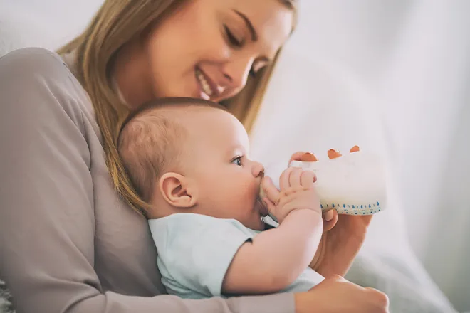 Mother holding baby in position while feeding to prevent hiccups.