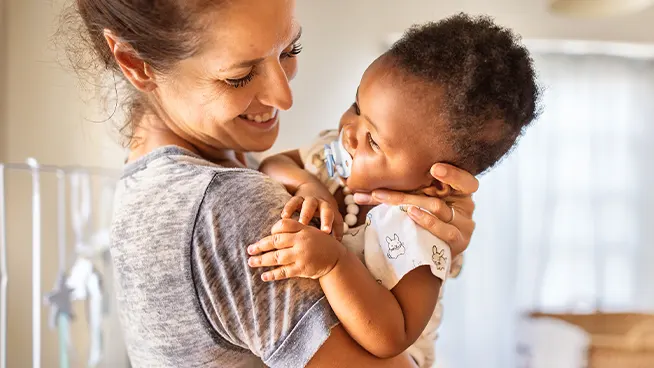 Mom holding infant who's sucking on a pacifier