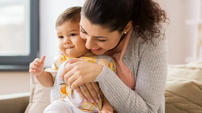 Madre con sus brazos abrazados amorosamente alrededor de su bebé