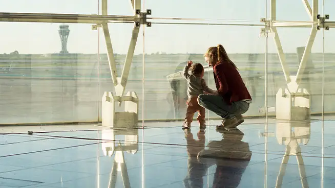 Madre y niño mirando por una ventana en el aeropuerto