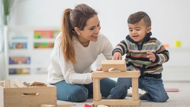 Mamá y niño pequeño jugando con bloques de apilamiento