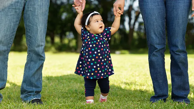 Niño caminando de la mano de sus padres