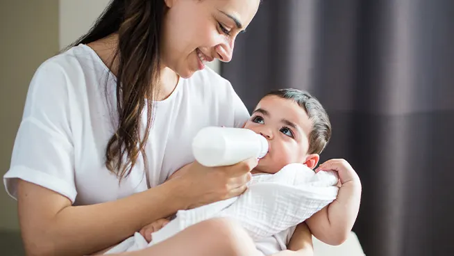 Madre mirando dulcemente a su bebé mientras le da el biberón