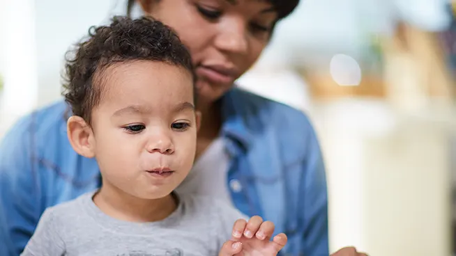 Niño pequeño sentado en el regazo de su madre