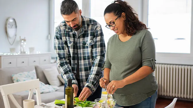 Un hombre y una mujer preparan comida juntos en la encimera de la cocina