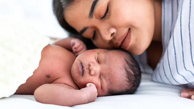 Una madre descansa tranquilamente su rostro junto a su bebé dormido