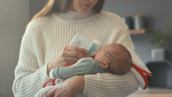 New mom cradling and bottle feeding newborn