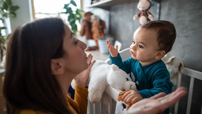 Madre haciendo un gesto a su bebé en la cuna