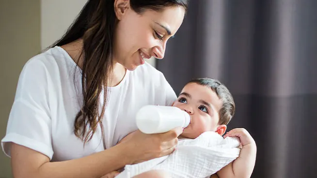 Mom cradling baby and feeding with a bottle