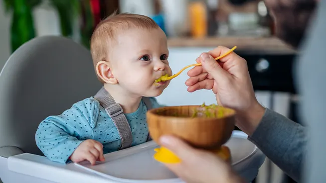 Baby in a high chair being spoon fed