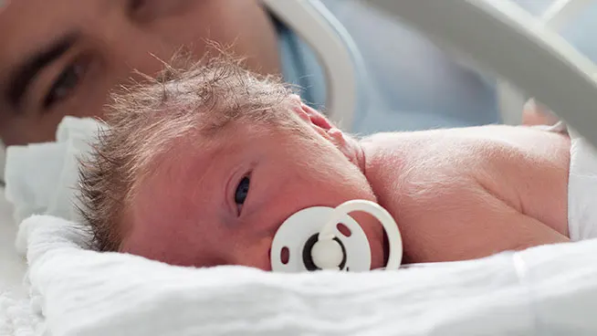 Premature baby on blanket with pacifier