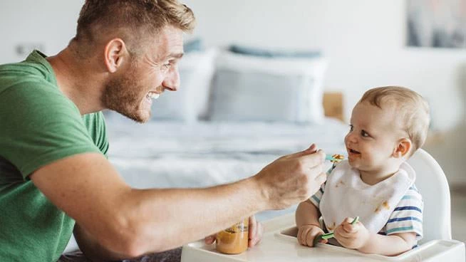 Dad feeding baby soft food