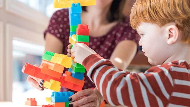 Niño pequeño jugando a apilar bloques con mamá