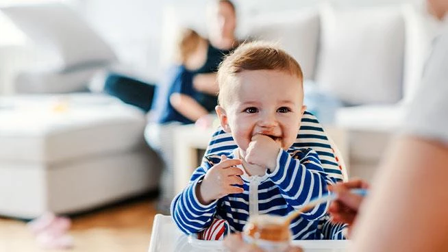 Baby sitting in a high chair eating baby food