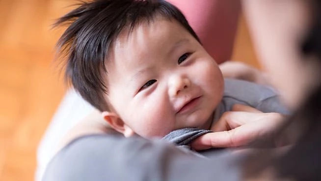 Infant smiling up at mom