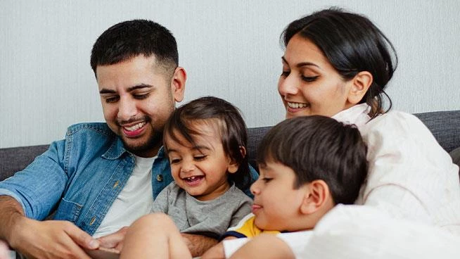 Familia sentada en el sofá juntos mirando un teléfono