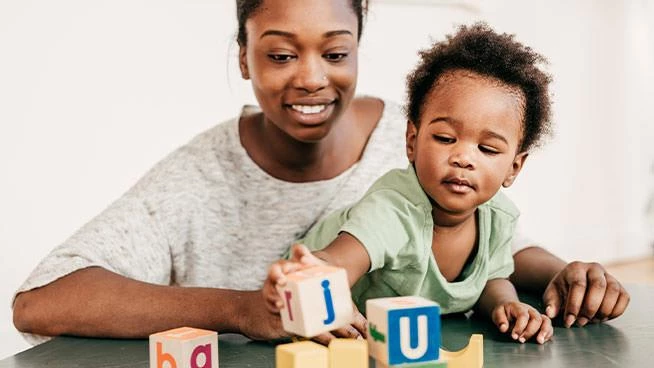 Mom and toddler son playing with building blocks