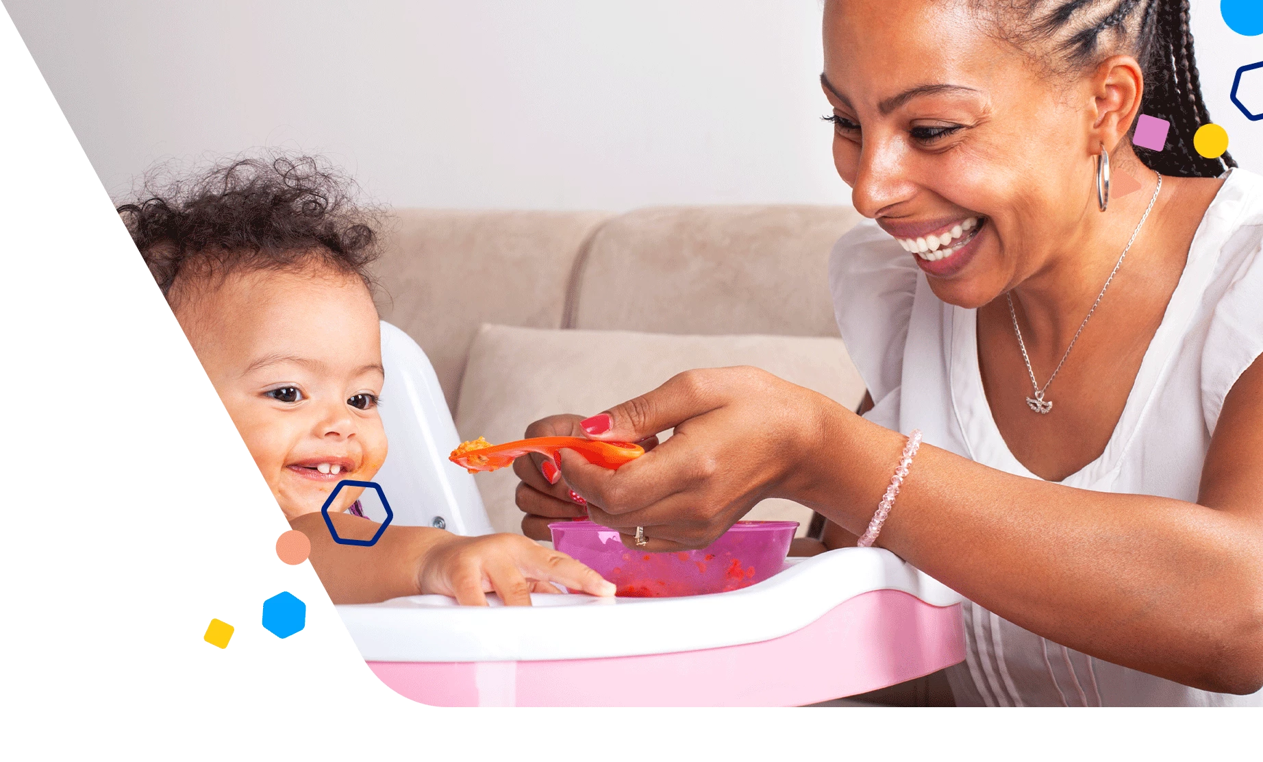 Baby in a high chair being spoon-fed by mom