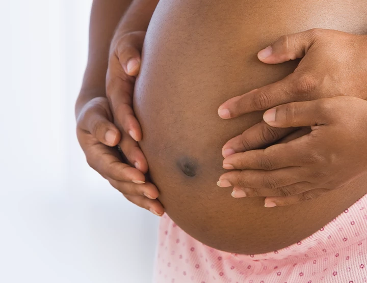 Pregnant woman and spouse's hands holding her belly