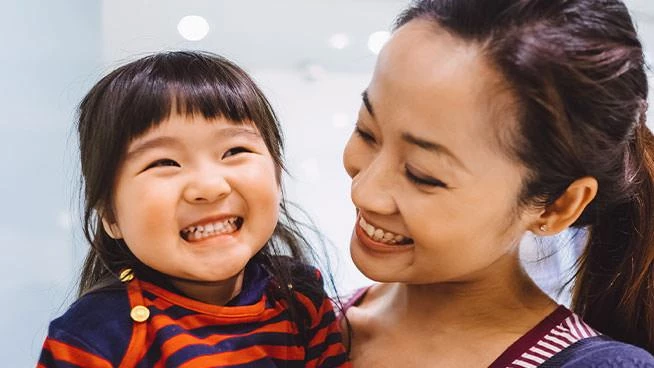 Mamá sonriendo amorosamente a su niña pequeña