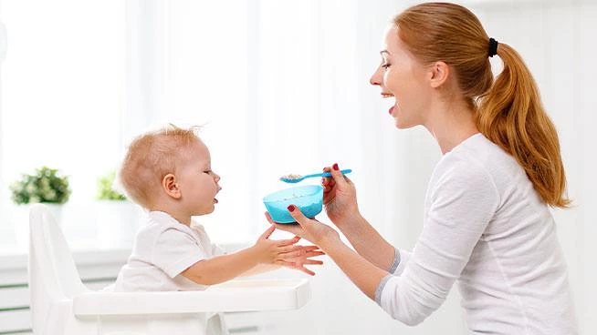 Mom feeding toddler cereal