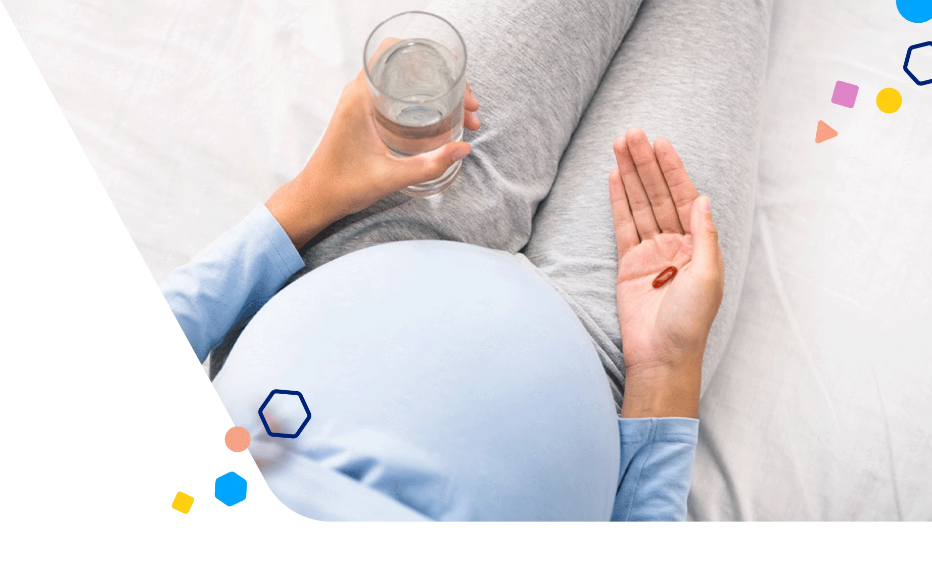 Pregnant woman holding prenatal vitamin and a glass of water