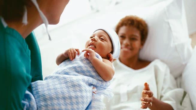 Nurse handing baby to new mom