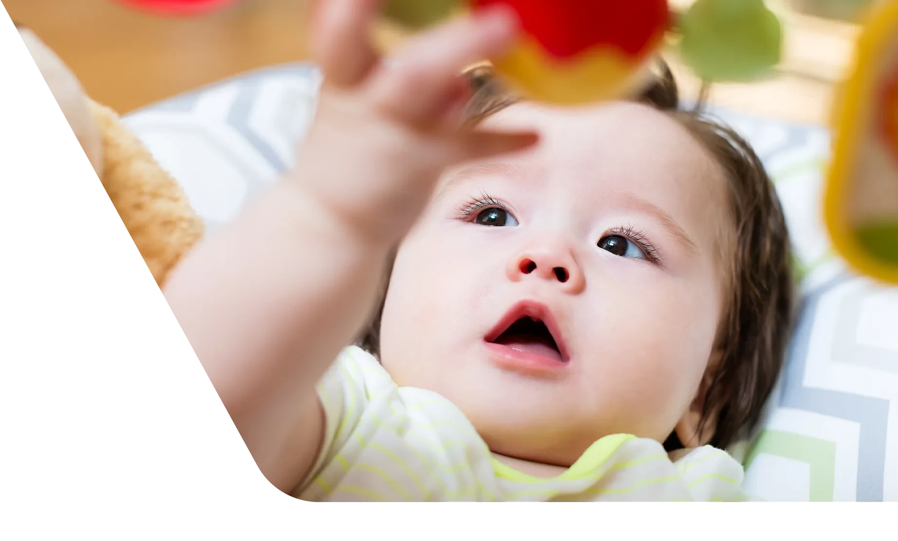 baby playing with toy while lying on a play mat