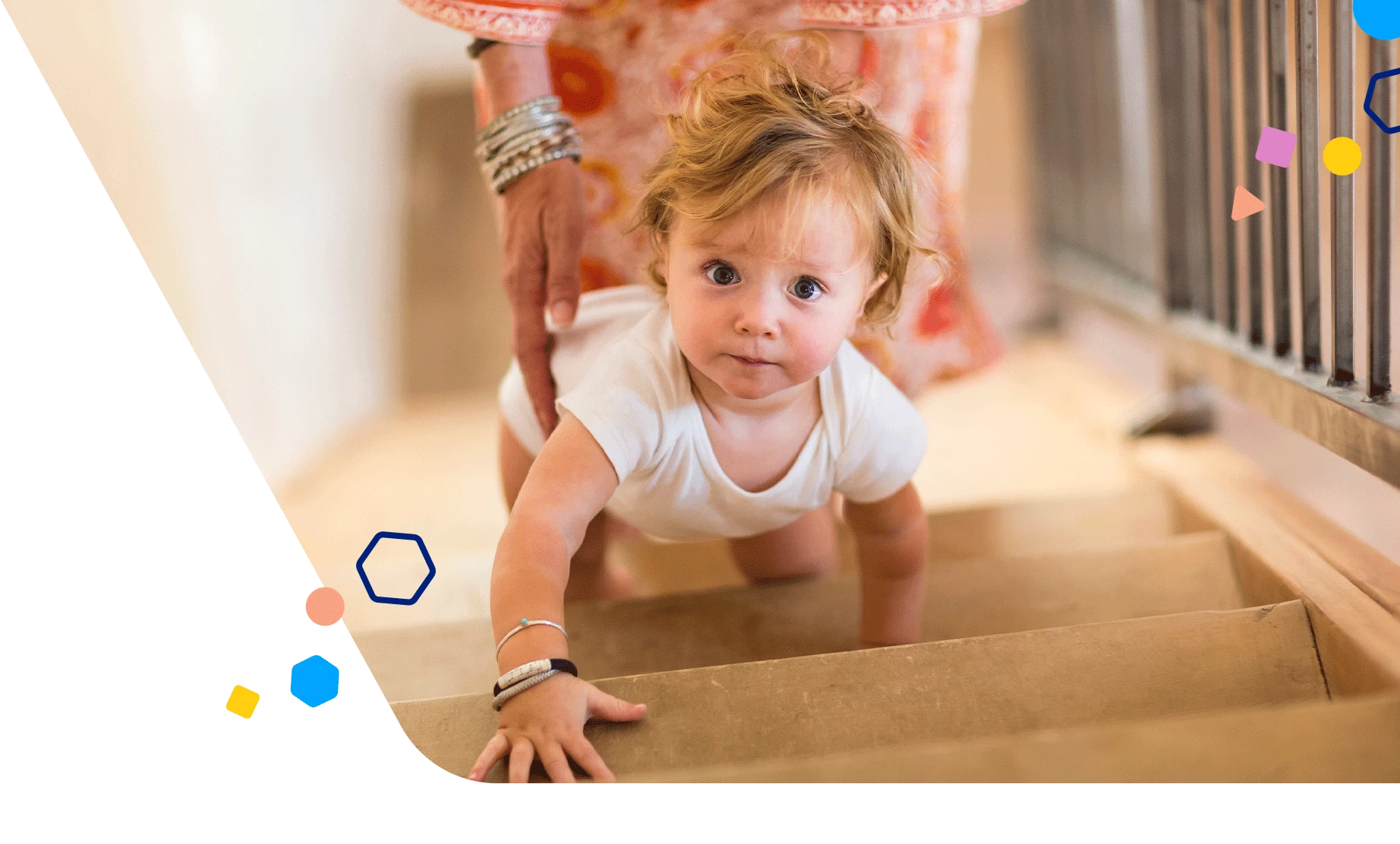 Toddler boy crawling up the stairs as his mom follows behind him