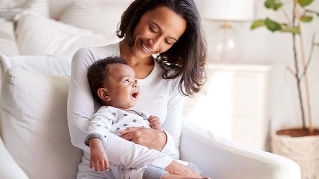 Mom holding infant while sitting in white chair