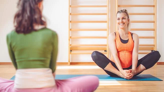 Pregnant woman and instructor doing prenatal yoga