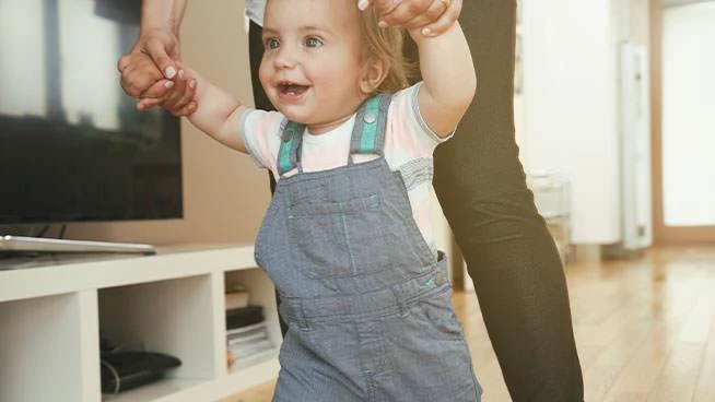 Parent helping 11 month old toddler walk