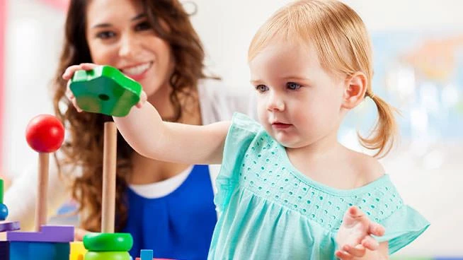 Niña pequeña jugando con un juguete apilable con su mamá