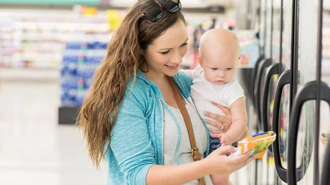 Mom and baby at the grocery store looking at frozen veggies