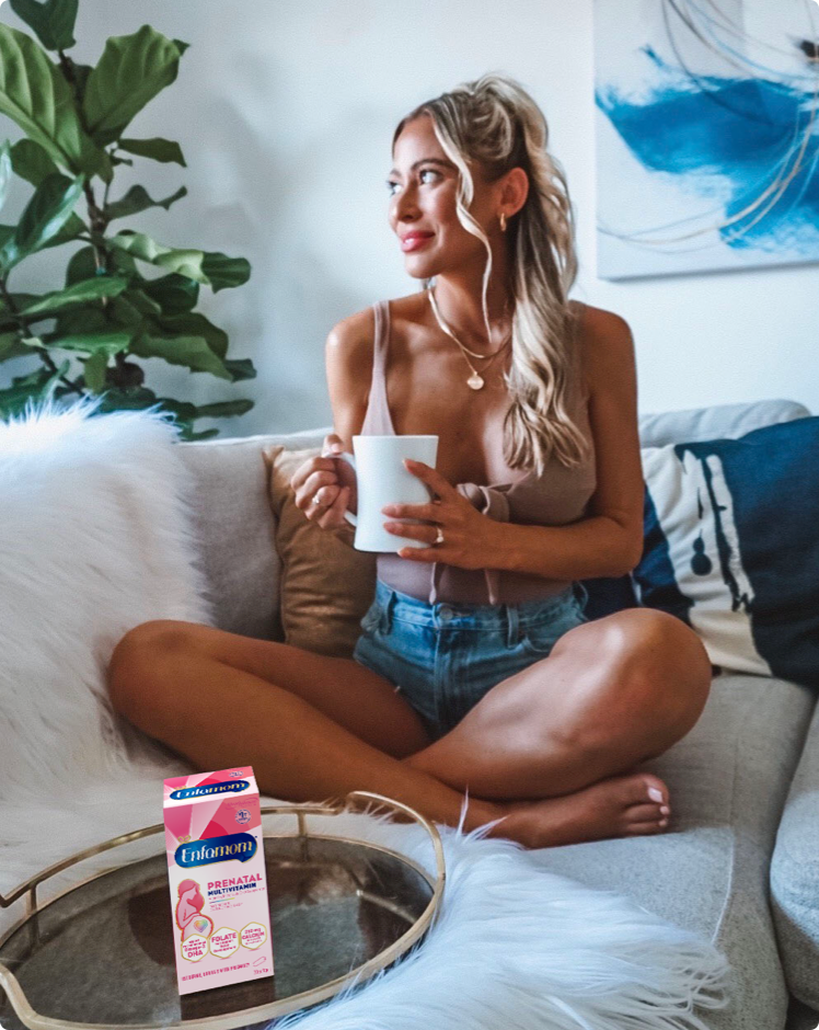 Mujer mirando por la ventana con vitaminas prenatales Enfamom™