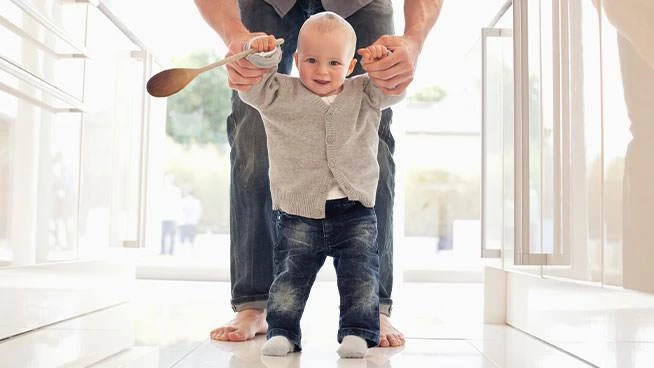 Dad helping toddler walk