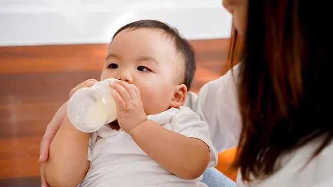 Mom holding baby as they drink a bottle