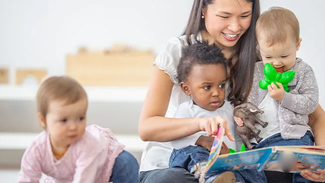 Daycare professional paying with group of toddlers