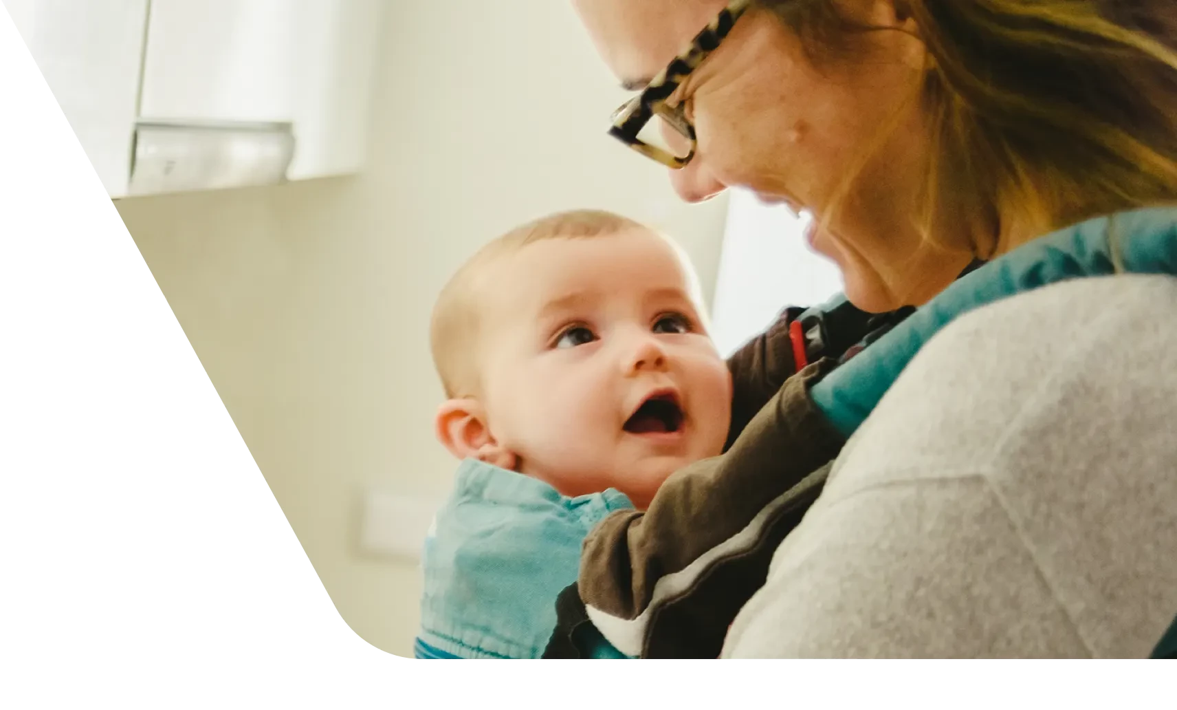 Smiling mom holding happy baby in a carrier