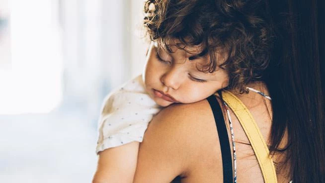 Niño pequeño durmiendo sobre el hombro de su madre