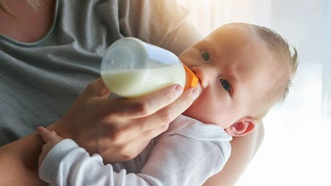 bebé en brazos de mamá que toma el biberón