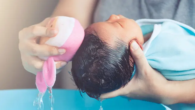 Mom bathing newborn baby