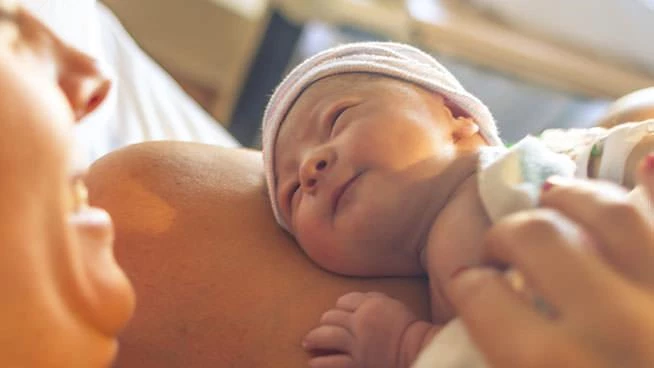 Mom smiling at newborn in delivery room