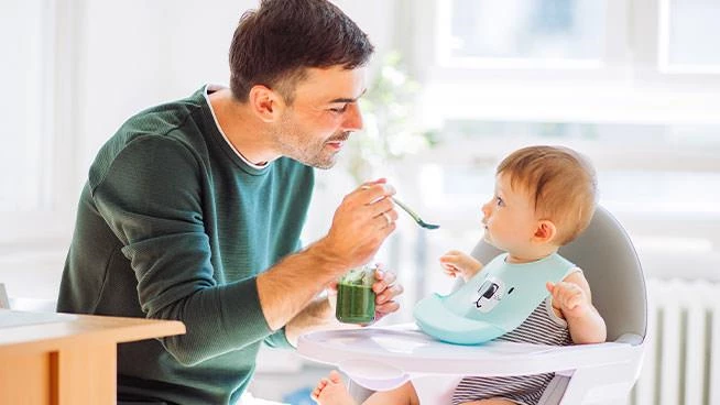 Dad feeding baby in high chair