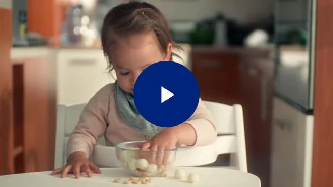 Niño pequeño comiendo fresas con su mamá sentada junto a él