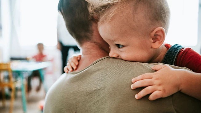 Toddler laying on dad's shoulder