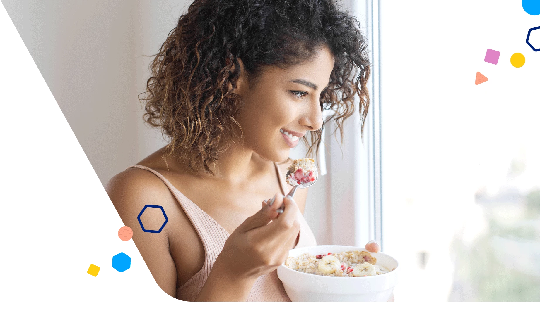 Woman eating a bowl of oatmeal with bananas and berries