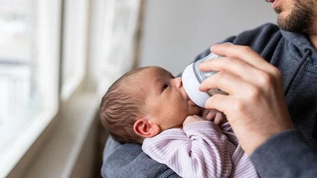 Dad feeding newborn baby a bottle