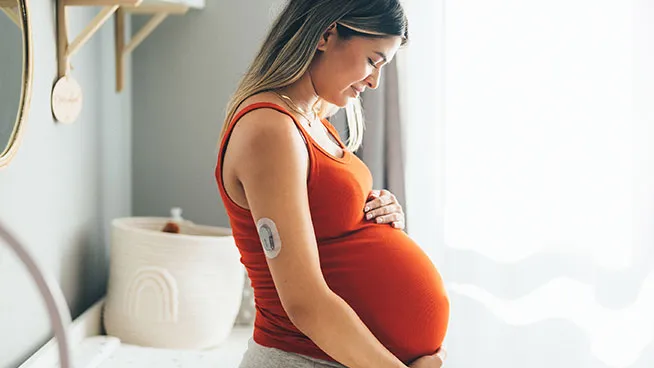 Smiling pregnant woman feeling her baby move.