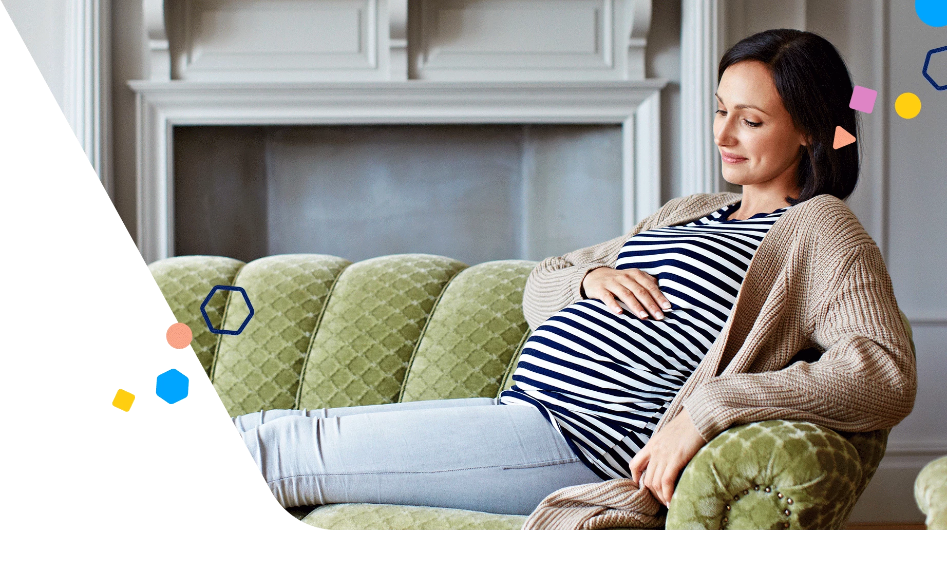 Pregnant woman sitting on a green couch holding her bump